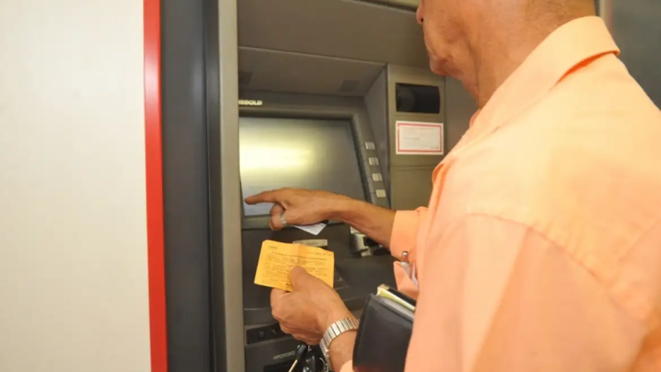 Homem tentando sacar dinheiro em caixa eletrônico de banco. Foto: Agência Brasil.
