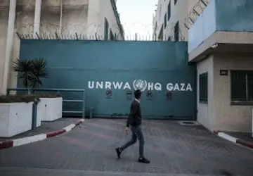 Homem caminha em frente ao prédio da Agência de Assistência e Obras das Nações Unidas (UNRWA) na Cidade de Gaza Ali Jadallah/Agência Anadolu via Getty Images